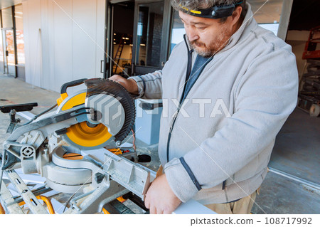 Working on chop saw tool trim worker cuts base wooden moldings Working on chop saw tool trim worker cuts base wooden moldings 108717992