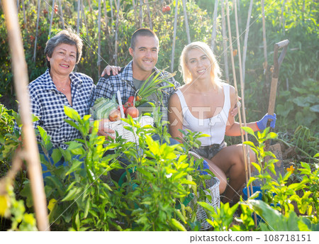 Family in garden posing with harvested vegetables 108718151
