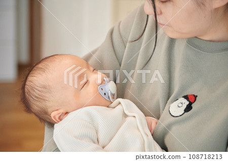 Mother putting her to sleep in her arms, sleeping baby, childcare 108718213