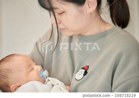Mother putting her to sleep in her arms, sleeping baby, childcare 108718219
