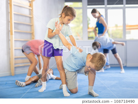 Children, boy and girl, working in pair mastering new self-defense moves at gym 108718490