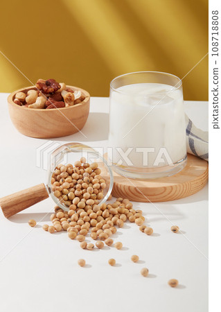 A lot of soybeans displayed on white surface with a cup of milk and wooden bowl of many nuts.Research suggests that nuts and beans may reduce inflammation A lot of soybeans displayed on white surface with a cup of milk and wooden bowl of many nuts.Research suggests that nuts and beans may reduce inflammation 108718808