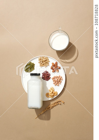 Glass bottle and cup filled with milk and a ceramic dish featured variety of nuts. Soybean (Glycine max) can boost the production of collagen 108718828