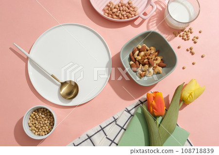 Various nuts and beans are arranged over pink background. Ceramic dish with blank space to show your product extracted from organic nuts and beans 108718839