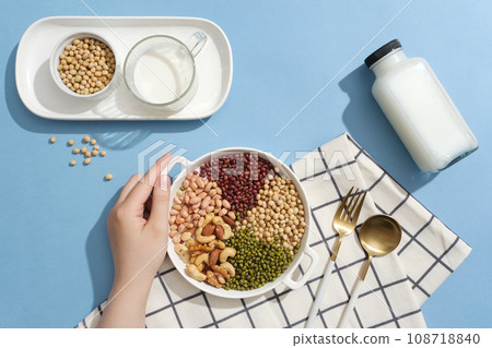 Many types of nuts and beans are contained inside a dish. Empty label bottle and a cup filled with milk. Nuts and beans have been shown to promote weight loss 108718840
