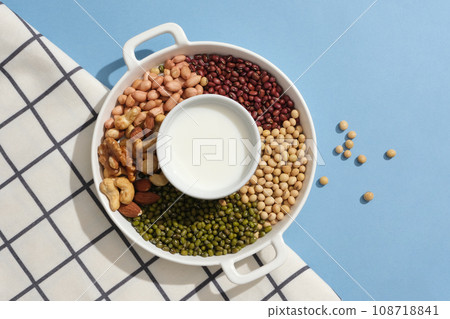 Peanuts, almonds, cashew nuts, green beans, soybeans and red beans are surrounded a bowl of milk. Nuts and beans are essential for overall health 108718841