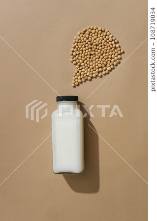 Minimal scene of an unlabeled glass bottle filled with milk displayed with a handful of soybeans. Mockup of skin care cosmetic extracted from Soybean (Glycine max) Minimal scene of an unlabeled glass bottle filled with milk displayed with a handful of soybeans. Mockup of skin care cosmetic extracted from Soybean (Glycine max) 108719034