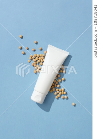Blue surface featured a lot of soybeans and a white tube without label. Creams that contain soybeans can help reduce the signs of sun damage on your skin 108719043