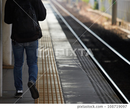 A man walking on a station platform during morning commuting hours A man walking on a station platform during morning commuting hours 108719097