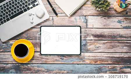 Wooden desk workplace with blank screen tablet, laptop, pen, noebook and cup of coffee, Top view flat lay with copy space. 108719170