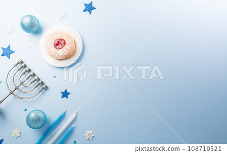 Jewish holiday Hanukkah concept. Top view of sweet donuts, menorah and candles on blue background. Jewish holiday Hanukkah concept. Top view of sweet donuts, menorah and candles on blue background. 108719521