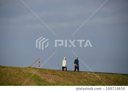 A senior couple taking a walk on the coastal embankment in autumn A senior couple taking a walk on the coastal embankment in autumn 108719656