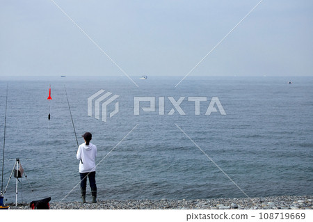 一位年輕女子早上在海灘上釣魚 108719669