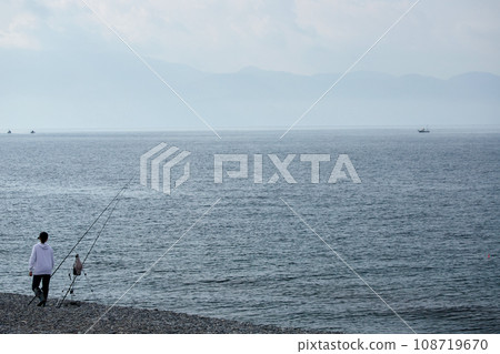 A young woman fishing in the sea on the beach in the morning A young woman fishing in the sea on the beach in the morning 108719670