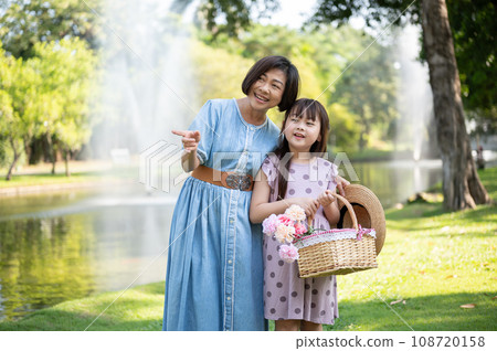 Happy and kind Asian grandmother is walking and having fun in the park with her lovely granddaughter Happy and kind Asian grandmother is walking and having fun in the park with her lovely granddaughter 108720158