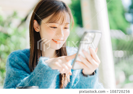 在露台上看智慧型手機的女人 108720256