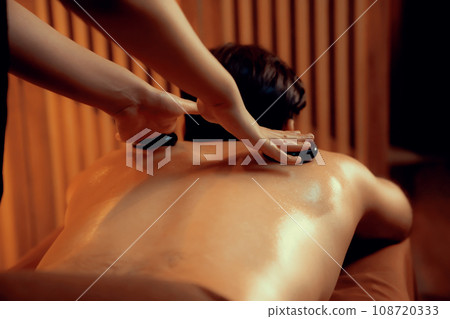 Hot stone massage at spa salon in luxury resort with warm candle light.Quiescent Hot stone massage at spa salon in luxury resort with warm candle light.Quiescent 108720333