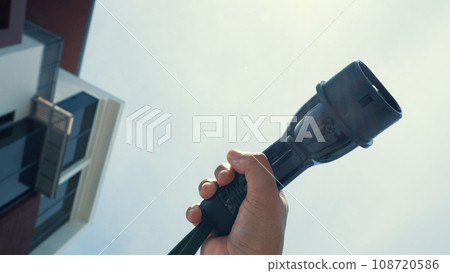 Closeup hand grasping an EV plug for electric vehicle as progressive idea. Closeup hand grasping an EV plug for electric vehicle as progressive idea. 108720586