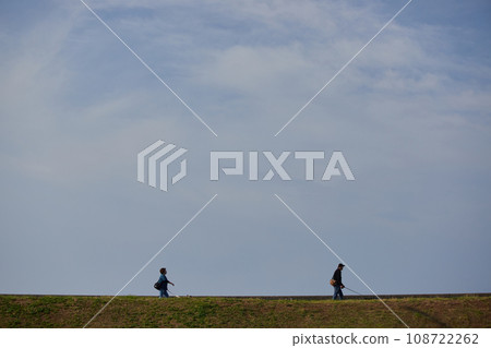 一對夫婦帶著他們的狗在海堤上散步 一對夫婦帶著他們的狗在海堤上散步 108722262