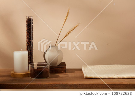 On the wooden pedestal, glassware container coffee bean and coffee powder decorated with candle, vase and towel. Space for cosmetic product mockup display, which extracted from coffee 108722628