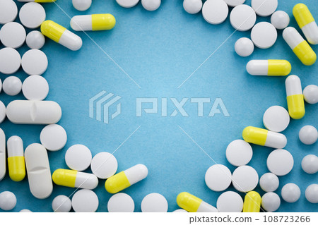Frame made of assorted pills on blue background, flat lay with space for text 108723266