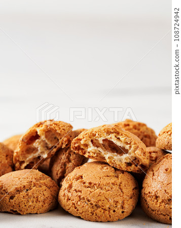 pile of cookie amaretti on white marble background - traditional Italian Sardinian pastry. Amaretti biscuit cookies made from almond or apricot kernels with copy space. Vertical 108724942