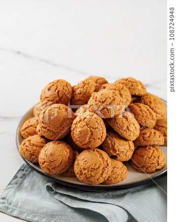 Plate of cookie amaretti on white marble background - traditional Italian Sardinian pastry. Delicious amaretti biscuit cookies made from almond or apricot kernels with copy space Plate of cookie amaretti on white marble background - traditional Italian Sardinian pastry. Delicious amaretti biscuit cookies made from almond or apricot kernels with copy space 108724948