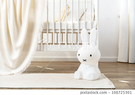 Baby wooden crib and toy rabbit in nursery room Baby wooden crib and toy rabbit in nursery room 108725301