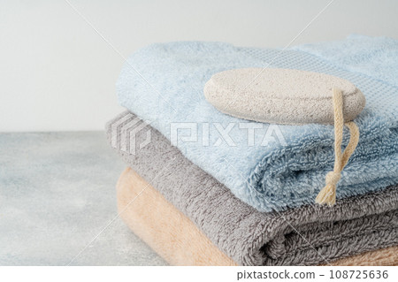 Pumice stone and stacked towels in a bathroom Pumice stone and stacked towels in a bathroom 108725636