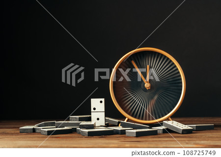 Domino tiles and clock on wooden table against black background 108725749