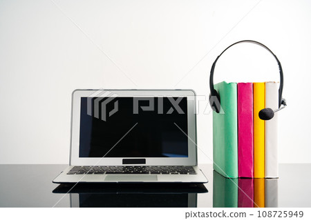 Stack of books, laptop and headphones on working table Stack of books, laptop and headphones on working table 108725949
