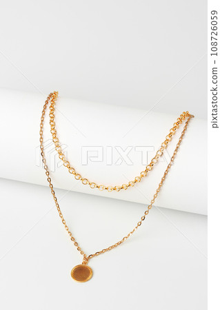 Golden chain with pendant on paper background close up 108726059
