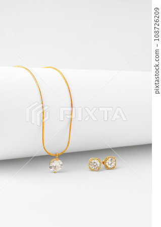 Golden necklace and diamond earrings on white paper background 108726209