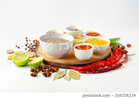Bowls with spices on wooden board on white background Bowls with spices on wooden board on white background 108726224