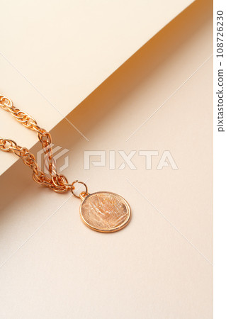 Golden chain with pendant on paper background close up Golden chain with pendant on paper background close up 108726230
