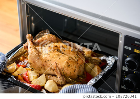 Remove the roasted chicken from the oven 108726341