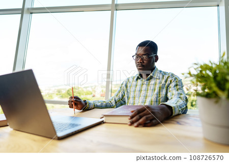 Serious concentrated african man studying or working with laptop indoors 108726570