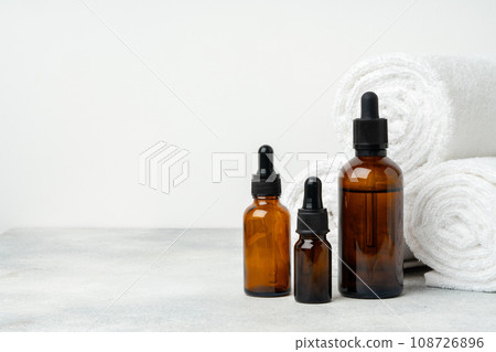 Cosmetic oil bottles and towels on gray background 108726896