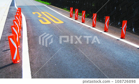 Scenery of an asphalt road with a sign that the width has been reduced Scenery of an asphalt road with a sign that the width has been reduced 108726898