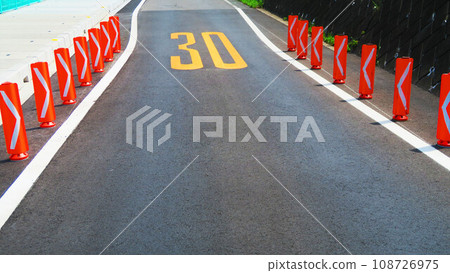 Scenery of an asphalt road with a sign that the width has been reduced 108726975