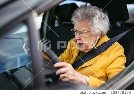Focused senior woman driving car alone, holding steering wheel firmly. Safe driving for elderly adults, older driver safety. 108728139