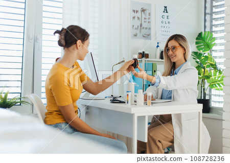 Teenage girl consulting on vitamins or supplements usage with paediatrician. Doctor prescribing medication to ill teenage girl. Concept of preventive health care for adolescents. Teenage girl consulting on vitamins or supplements usage with paediatrician. Doctor prescribing medication to ill teenage girl. Concept of preventive health care for adolescents. 108728236