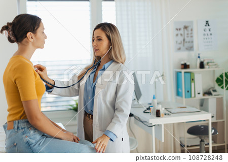 Doctor listening girl's breathing, heartbeats using a stethoscope. Teenage girl visiting paediatrician for annual preventive physical examination. Concept of preventive health care for adolescents Doctor listening girl's breathing, heartbeats using a stethoscope. Teenage girl visiting paediatrician for annual preventive physical examination. Concept of preventive health care for adolescents 108728248