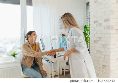Teenage patient arriving at appointment with doctor, shaking hands with female pediatrician, physician. Teen girl have consultation, first visit with gynecologist. Concept of preventive health care 108728258