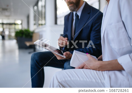 Close up of pharmaceutical sales representative talking with female doctor in medical building. Hospital director consulting with healthcare staff. 108728261