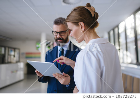 Pharmaceutical sales representative talking with female doctor in medical building. Hospital director consulting with healthcare staff. Pharmaceutical sales representative talking with female doctor in medical building. Hospital director consulting with healthcare staff. 108728275