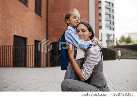 Working mother hugging daughter in front of the school building, and heading to work. Concept of work-life balance for women. Working mother hugging daughter in front of the school building, and heading to work. Concept of work-life balance for women. 108728395