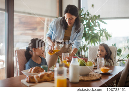 Mother prepares breakfast for children, in the morning. Maternal love and care for household and family. 108728461