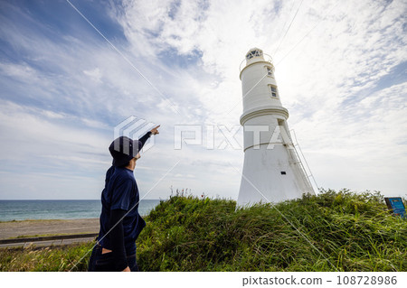 A man points to a lighthouse and says something A man points to a lighthouse and says something 108728986