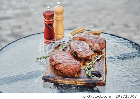 Tree juicy grilled strip steaks on wooden cutting board 108729308